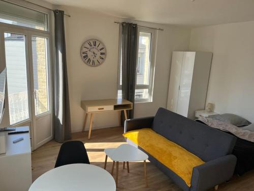 a living room with a couch and a clock on the wall at Le Lumineux in Le Havre