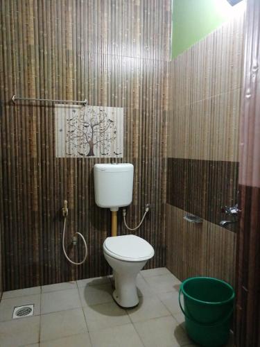 a bathroom with a toilet and a green bucket at Tapovan fruitopia in Sultan Bathery