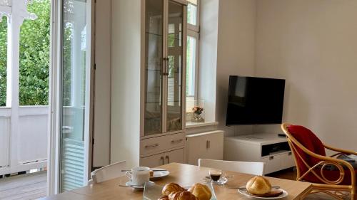 a living room with a table and a television at Villa Sonneck - Wohnung 7 in Ostseebad Sellin