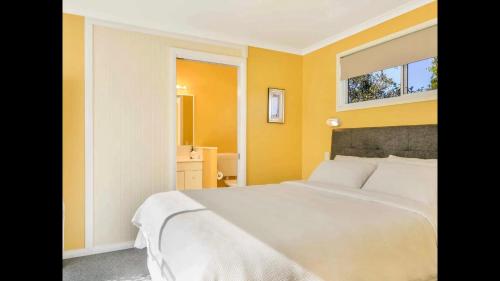 a bedroom with a white bed and a mirror at Orange Blossom- Comboyne Mountain Cottages in Comboyne