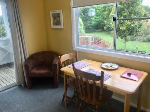 a dining room with a table and a chair and a window at Orange Blossom- Comboyne Mountain Cottages in Comboyne