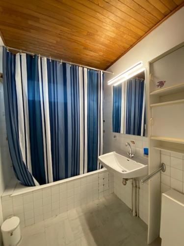 uma casa de banho com cortinas de duche azuis e brancas e um lavatório. em Boost Your Immo Les Deux Alpes 174 / Le Midi em Les Deux Alpes