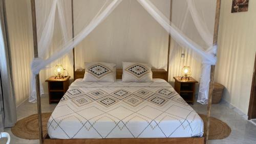 a bedroom with a white bed with two night stands at Villa Kounzo in Ndangane