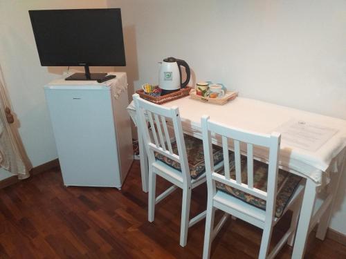 B&B le Villette Predappio في بريدابيو: طاولة بيضاء مع كرسيين وشاشة كمبيوتر