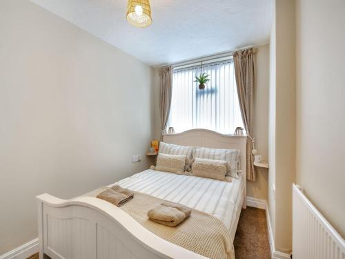 a small bedroom with a bed with a window at The Cottage in Rhyl