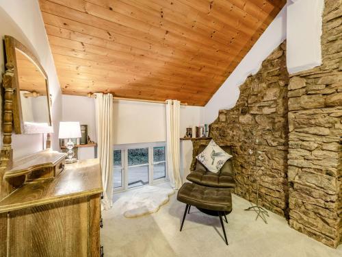uma sala de estar com uma parede de pedra e uma cadeira de couro em The Annex em Llanarthney