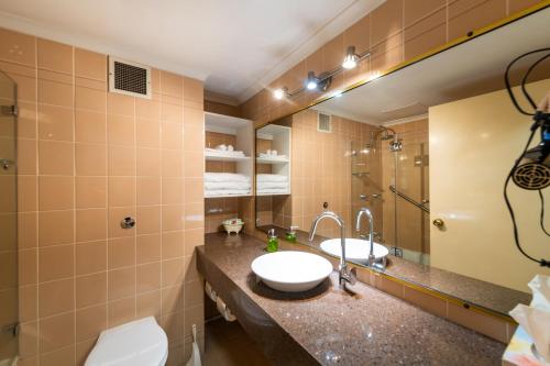 uma casa de banho com um lavatório e um espelho em Golden Age Motor Inn em Queanbeyan