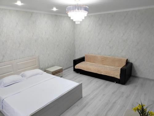a bedroom with a bed and a couch and a chandelier at ЖК комфорт in Kokshetau