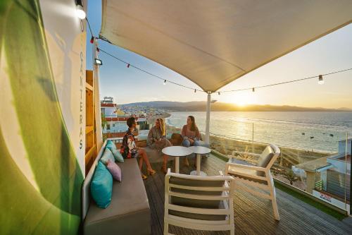 three women sitting on a balcony looking at the ocean at Hotel Aloe Canteras in Las Palmas de Gran Canaria