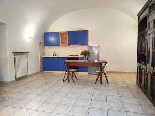 een keuken met blauwe kasten en een tafel met bloemen erop bij Intero alloggio: appartamento bilocale in Alessandria