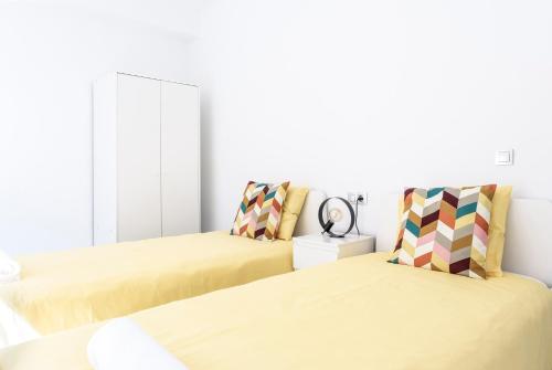 2 Betten in einem Zimmer mit gelber Bettwäsche in der Unterkunft Lovely 2-bedroom home in Pueblo Nuevo de Guadiaro in Guadiaro