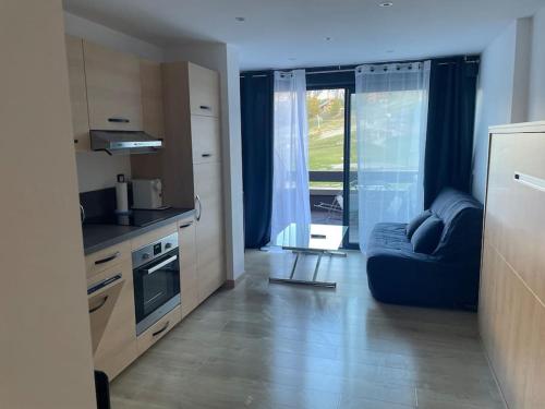 a kitchen with a blue couch in a small kitchen at Superbe studio front de neige la joue du loup in Le Dévoluy