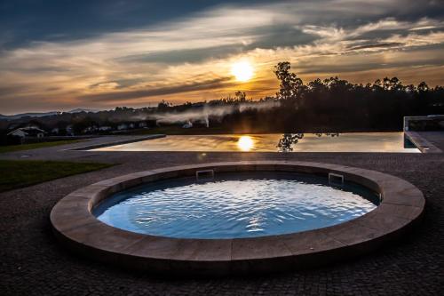una grande piscina d'acqua con tramonto sullo sfondo di Quinta do Esquilo - Hotel Rural a Rendufe
