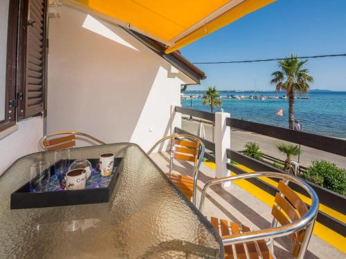 a table with cups and chairs on a balcony with the ocean at Apartments Sea Eyes in Vir