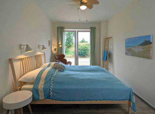 um quarto com uma cama azul e uma janela em App 7, Strandresidenz Dünenperle em Kühlungsborn