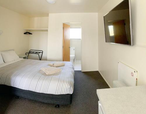 a small bedroom with a bed and a mirror at Adelaide Motel in Wellington