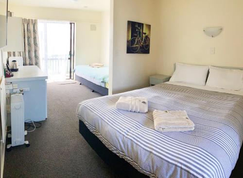 a bedroom with a large bed with towels on it at Adelaide Motel in Wellington