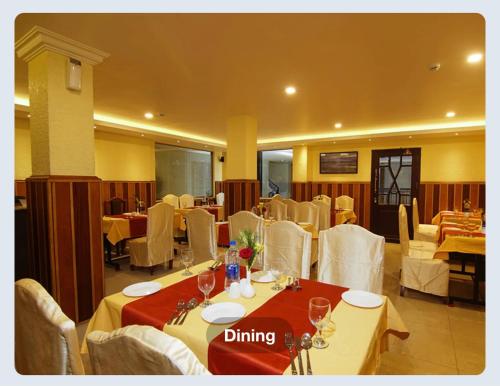 a dining room with white tables and white chairs at Hotel Sasthapuri in Kozhikode