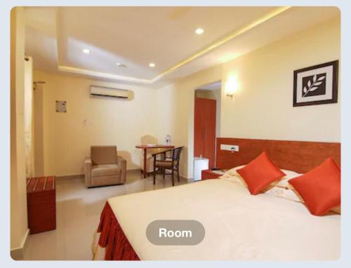 a room with a bed and a chair and a table at Hotel Sasthapuri in Kozhikode