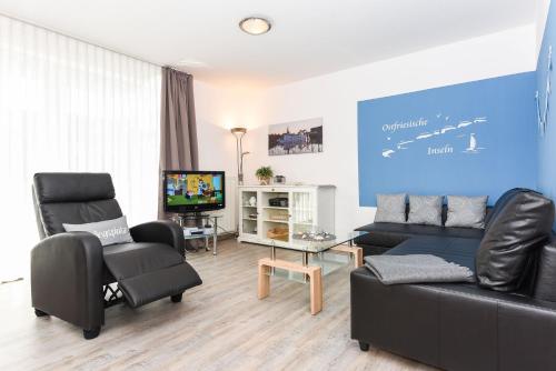 Una sala de estar con un sofá y sillas y un televisor. en Ferienwohnung to Huus, en Bensersiel