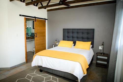 1 dormitorio con 1 cama grande con almohadas amarillas en Rock House at Benlize en Hartbeespoort