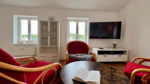 sala de estar con mesa, sillas y TV en Villa Sonneck - Wohnung 21, en Ostseebad Sellin