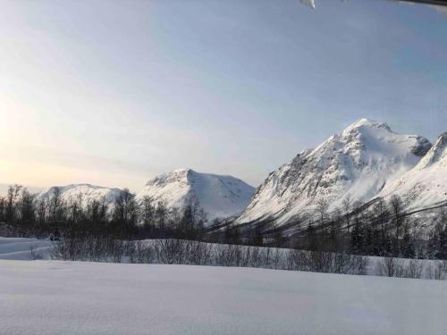 a snow covered mountain range with a field of snow at Mountainside Lodge - Breivikeidet in Tromsø