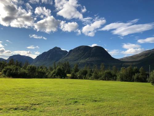 a green field with mountains in the background at Mountainside Lodge - Breivikeidet in Tromsø