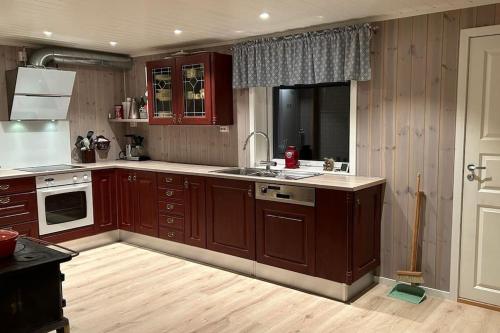 a kitchen with wooden cabinets and a sink and a stove at Mountainside Lodge - Breivikeidet in Tromsø