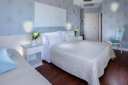 1 Schlafzimmer mit 2 Betten und einer weißen Tagesdecke in der Unterkunft Hotel Admiral - on the beach in Riccione