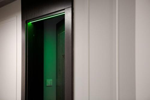 a hallway with a green door and a mirror at VICTORIA Hotel Klaipėda in Klaipėda