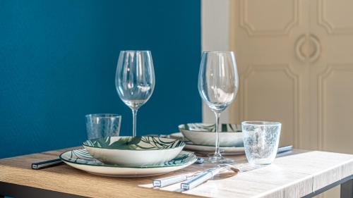 a table with two wine glasses and plates on it at Petit nid douillet - Welc'Home in Limoges
