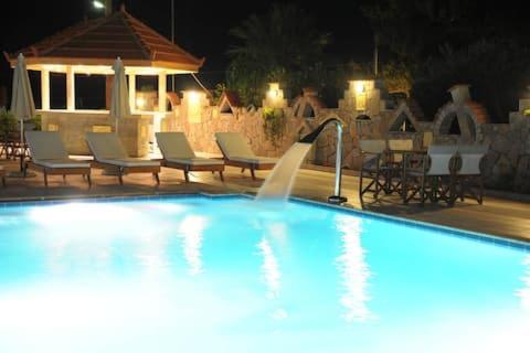 a swimming pool with chairs and a fountain at night at Evalia Apartments in Hersonissos