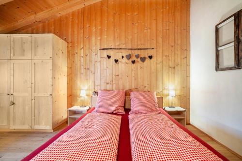 Cama grande en habitación con paredes de madera en Grushof App Paföl, en Sluderno