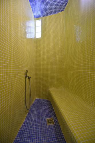 a yellow tiled bathroom with a shower and a tub at Villa Oliviers · Deluxe Villa - Infinity Pool & Helipad in Naousa