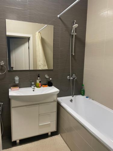bagno con lavandino, vasca e specchio di Квартира в центре Нур-Султана a Astana