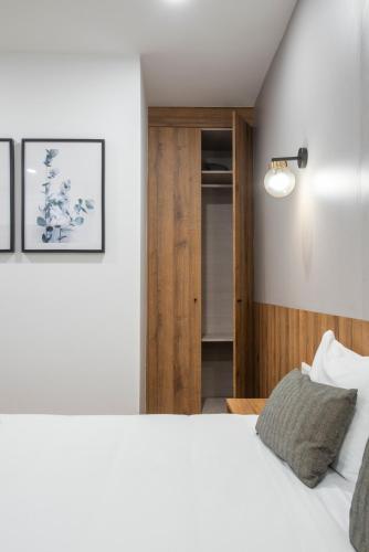 a bedroom with a white bed and a wooden door at Hotel Rural Solar das Arcadas in Ponte de Lima