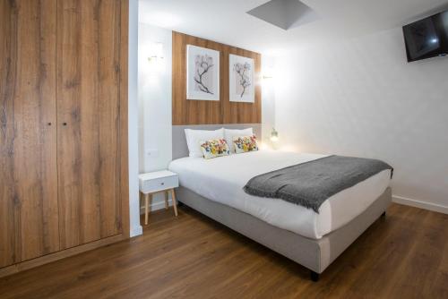a bedroom with a large white bed and wooden floors at Hotel Rural Solar das Arcadas in Ponte de Lima