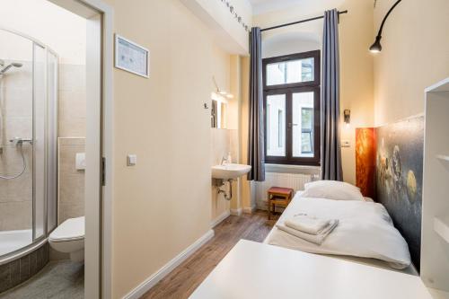a bathroom with a bed and a sink and a toilet at Hostel Mondpalast in Dresden