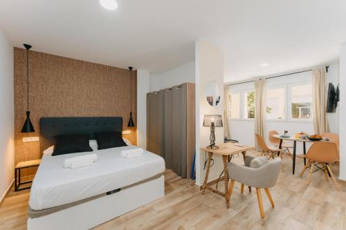 um quarto com uma cama, uma mesa e cadeiras em Coverlin Apartamentos San Francisco em Málaga
