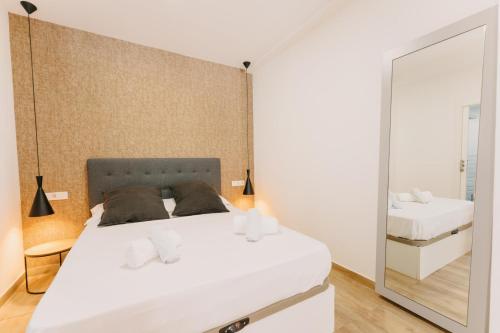 um quarto com uma grande cama branca e um espelho em Coverlin Apartamentos San Francisco em Málaga