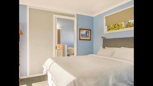 a bedroom with a white bed and a window at Apple Tree Cottage - Comboyne Mountain Cottages in Comboyne