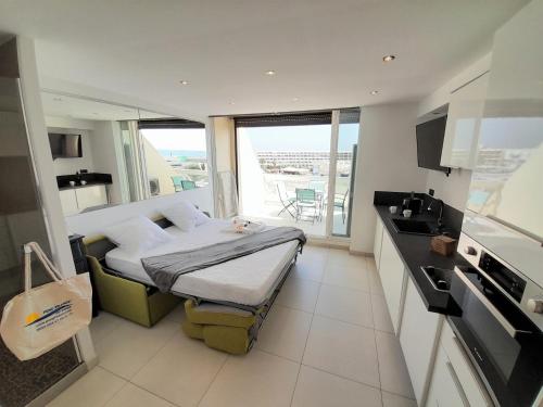 Cet appartement comprend une chambre avec un lit et une cuisine avec un balcon. dans l'établissement Studio Village Naturiste O Plaisir, au Cap d'Agde