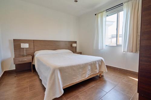 Riviera del Sur - Apart hotel في ميرامار: غرفة نوم بسرير كبير ونافذة