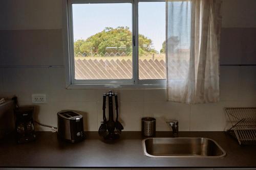 um balcão de cozinha com um lavatório e uma janela em Riviera del Sur - Apart hotel em Miramar