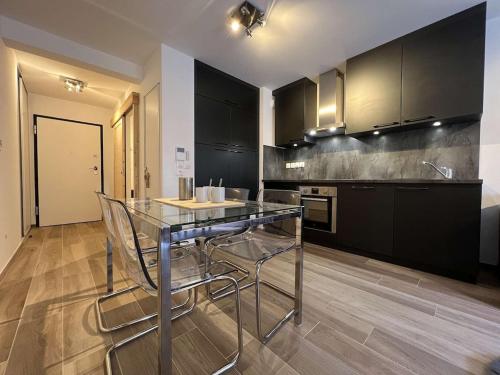 une cuisine avec une table en verre et des armoires noires dans l'établissement LES FREINETS - Apt D02 - BO Immobilier - Châtel - Multipass été 2025 offert, à Châtel