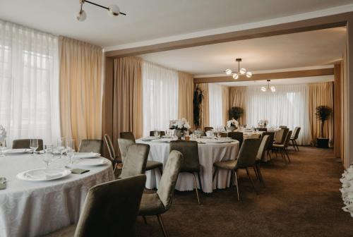 a dining room with tables and chairs with white tablecloths at Pensiunea Lido Moisei in Moisei