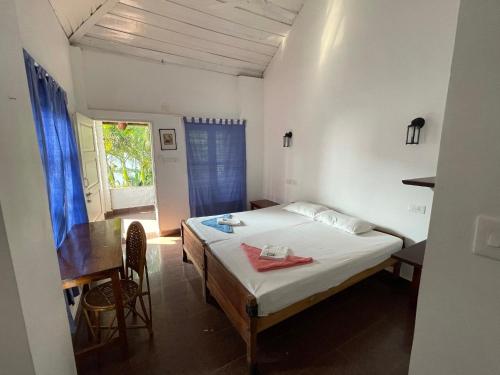 a bedroom with a bed and a desk and a window at The First Place Yogaresort, Odayam in Varkala