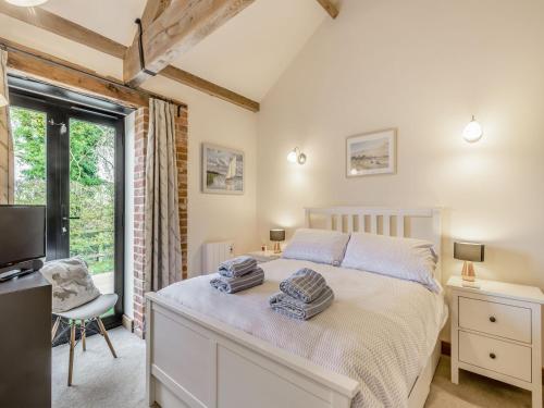 Ruperts Barn في Trimingham: غرفة نوم بسرير وتلفزيون ونافذة