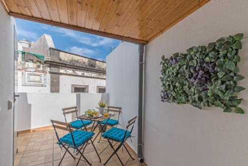 Home2Book Charming Attic Arucas Center, Terrace في أروكاس: طاولة وكراسي على شرفة مع وضع النباتات على الحائط
